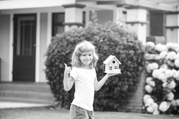 Enfant rêvant d'une nouvelle maison garçon heureux tenant une maison de rêve dans ses mains immobilier et assurance habitation