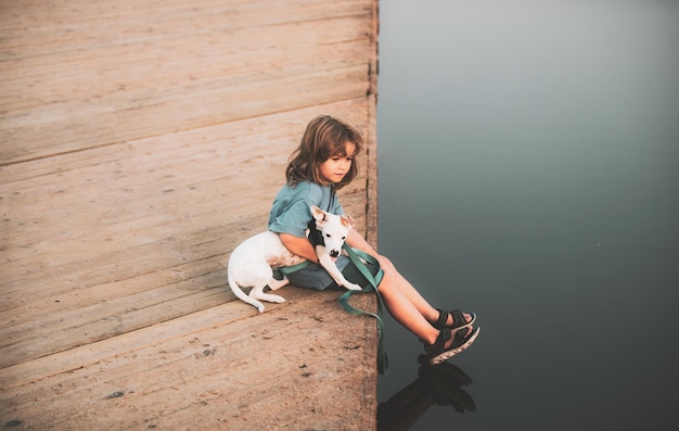 Enfant rêvant Petit enfant embrassant un chien chiot assis près du lac de l'enfance