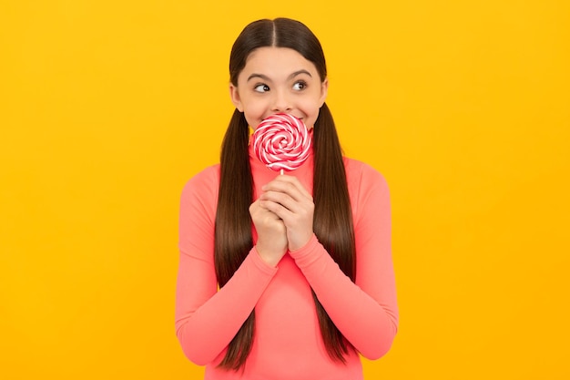 Enfant rêveur avec des bonbons sucette sur bâton sur fond jaune caramel