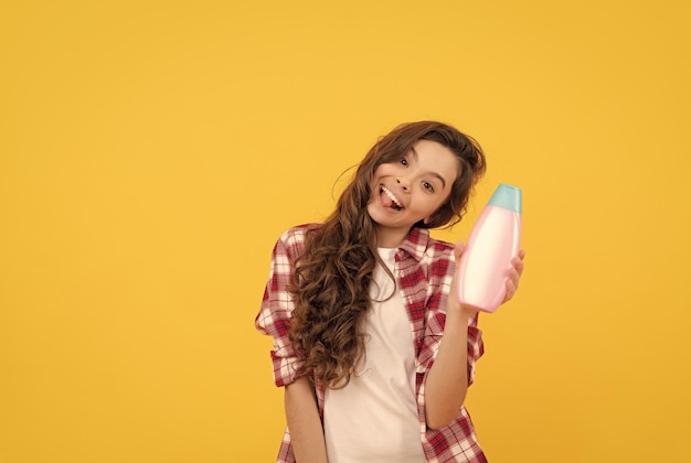 Enfant avec revitalisant cheveux longs bouclés habitudes quotidiennes et soins personnels présentant un produit cosmétique