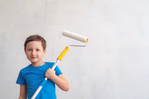 Enfant roule le rouleau dans la peinture sur le mur