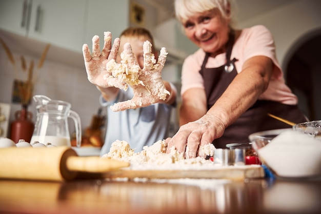 Enfant s'amusant à faire de la pâte en cuisinant avec grand-mère