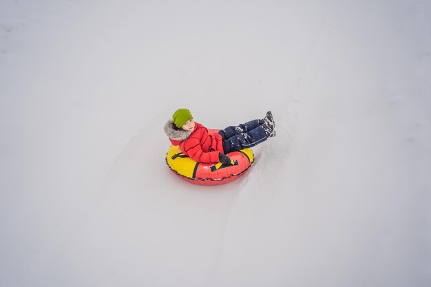 Enfant s'amusant sur un tube à neige Garçon monte sur un tube Plaisirs d'hiver pour les enfants