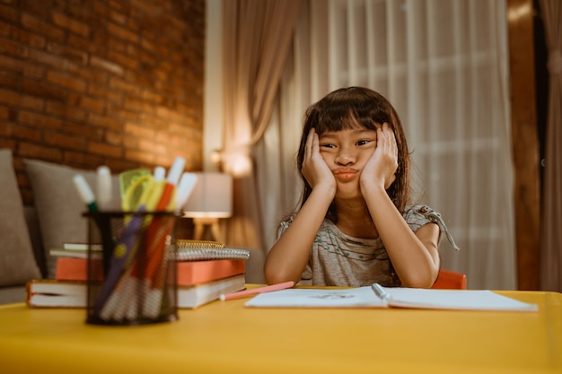 Une enfant s'ennuie en faisant ses devoirs