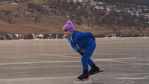 L'enfant s'entraîne sur le patinage de vitesse professionnel sur glace La fille patine en hiver dans des vêtements de sport costume de lunettes de sport Ralenti extérieur