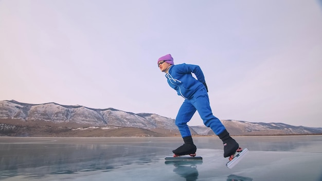 L'enfant s'entraîne sur le patinage de vitesse professionnel sur glace La fille patine en hiver dans des vêtements de sport costume de lunettes de sport Ralenti extérieur