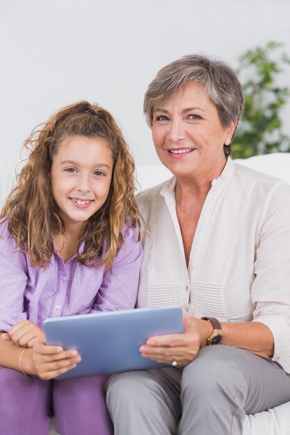 Enfant et sa grand-mère en regardant la caméra avec tablet pc