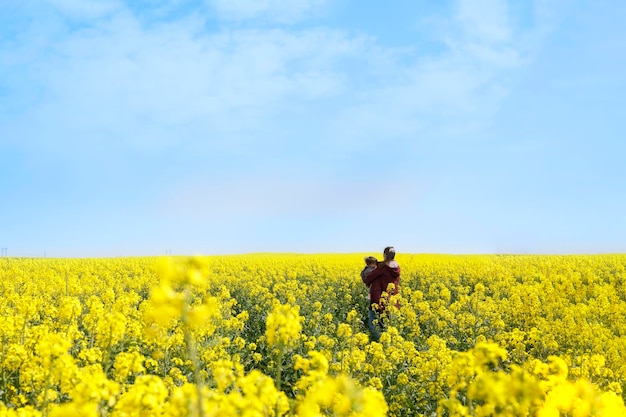 Enfant et sa mère tous deux réfugiés debout dans un champ de fleurs jaunes et un ciel bleu concept de drapeau ukrainien