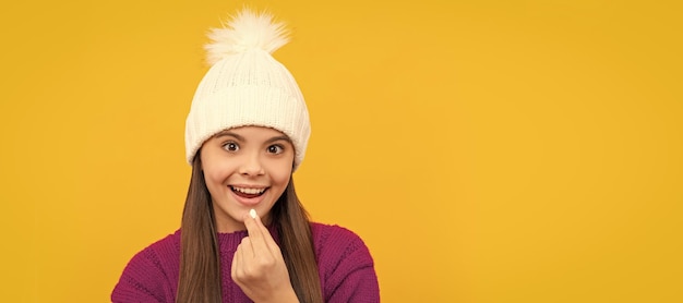 Enfant de la santé de l'enfance en chapeau d'hiver prenant la pilule complément alimentaire Affiche horizontale de l'espace de copie d'en-tête de bannière de visage d'enfant isolé