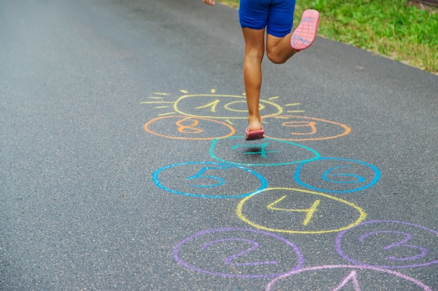 Enfant sautant des classiques sur le trottoir. Mise au point sélective.