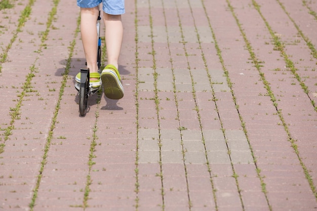 Enfant sur un scooter Pieds d'un enfant garçon avec des baskets sur un scooter lors d'une journée ensoleillée