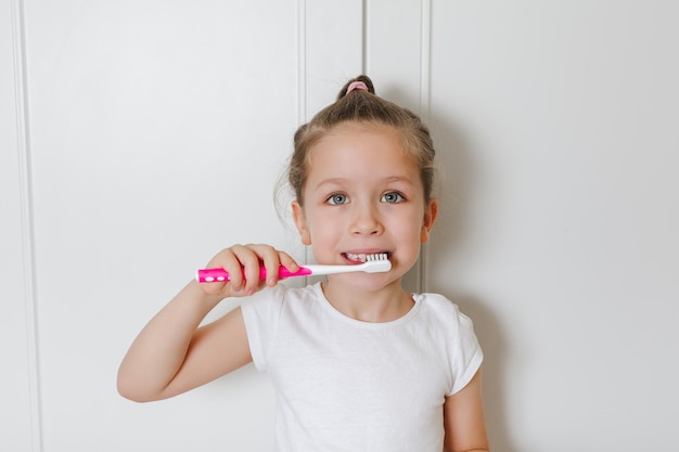 Un enfant se brosse les dents avec une brosse à dents rose Concept d'hygiène personnelle de santé dentaire de soins de santé