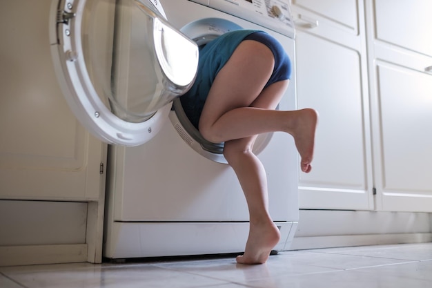 L'enfant se cache dans la machine à laver