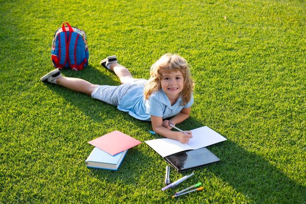 L'enfant se détend pendant les vacances L'enfant lit des livres sur fond d'herbe