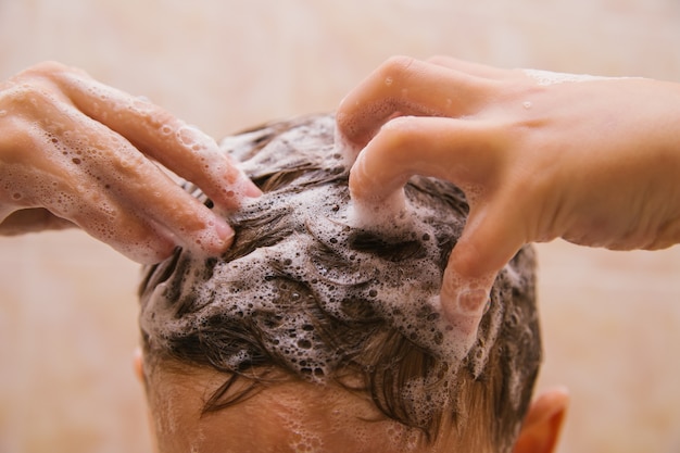 L'enfant se lave la tête avec du shampoing. Mousse de savon sur les cheveux. Soin des cheveux. Hygiène pour l'enfant.