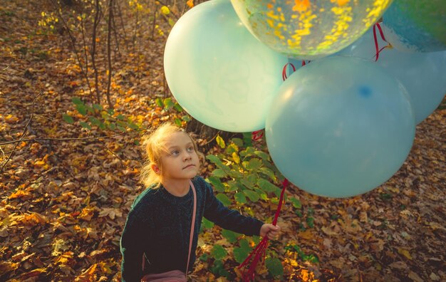 Un enfant se promène dans la forêt avec un tas de balles colorées Fille tenant des ballons colorés dans sa main