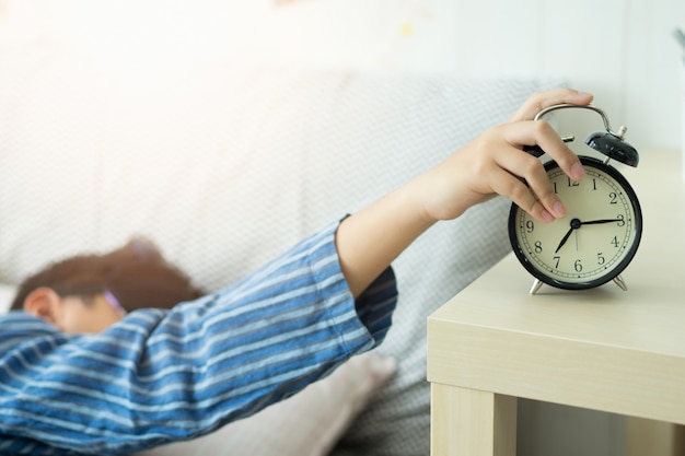 Un enfant se réveille avec un réveil dans la chambre