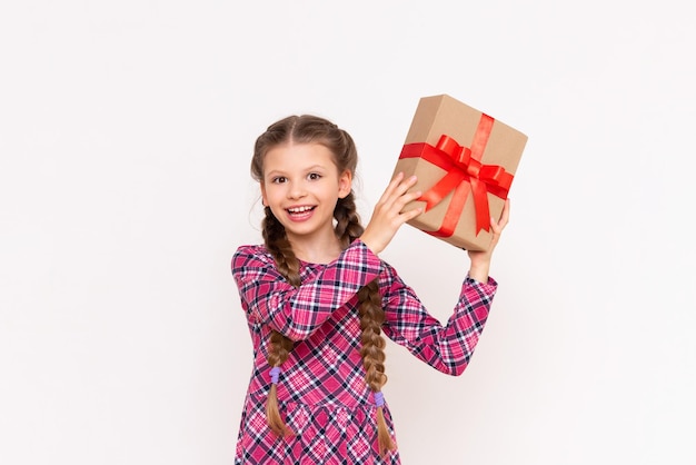 L'enfant secoue la boîte-cadeau et écoute ce qu'il y a dedans Concept de cadeau d'anniversaire Fond isolé blanc