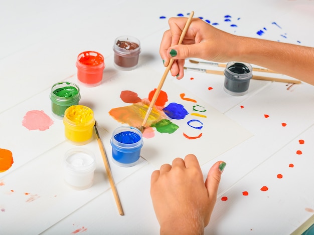 L'enfant Sélectionne La Couleur Souhaitée Sur Une Table En Bois Blanche.