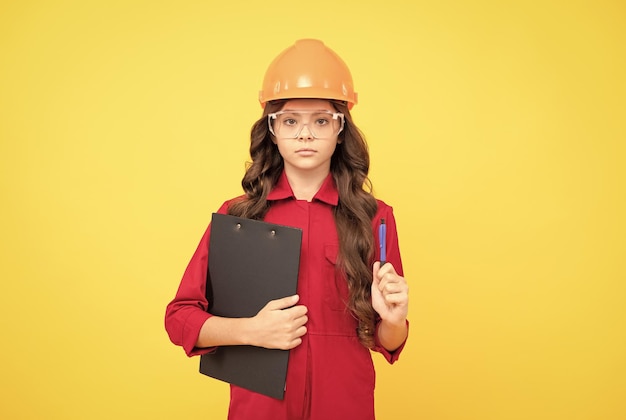 Une enfant sérieuse dans un casque de protection et des lunettes tient un dossier avec un expert en documents papier