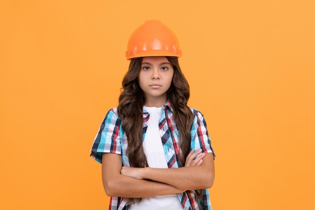 Enfant sérieux aux cheveux bouclés en casque de chantier, constructeur.