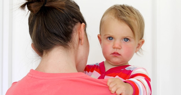 Enfant sérieux avec rouge effronté dans les mains de la mère