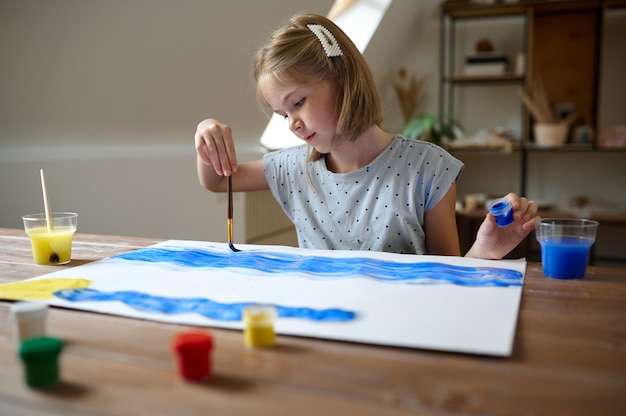 Enfant de sexe féminin dessin avec pinceau et peintures