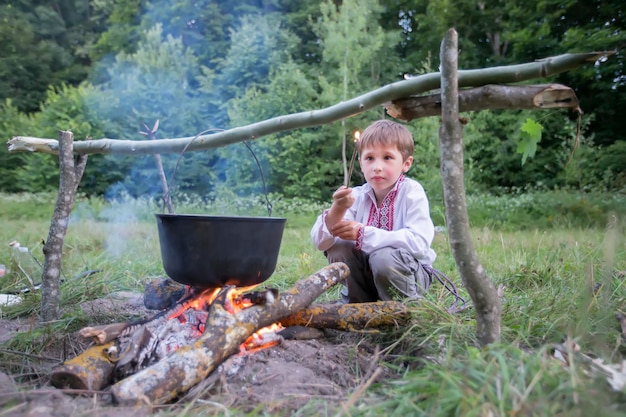Enfant slave en vêtements nationaux près du feu Garçon ukrainien dans la nature biélorusse