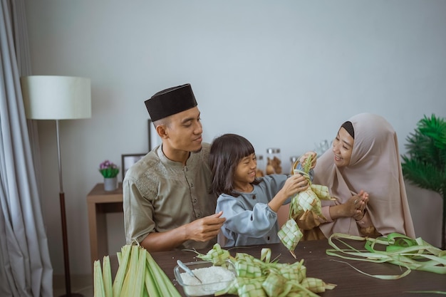 Enfant avec son parent faisant un ketupat à la maison