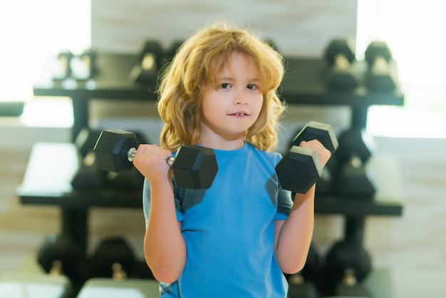 Photo enfant soulevant un haltère enfant mignon s'entraînant avec des haltères remise en forme pour enfants garçon enfant faisant de l'exercice avec des haltères enfants en bonne santé