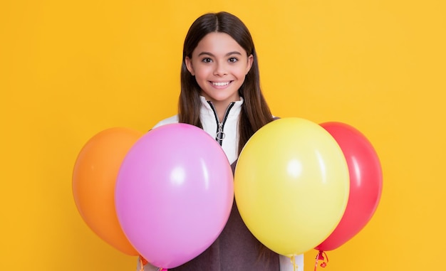 Enfant souriant avec des ballons colorés de fête sur fond jaune