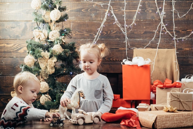 Enfant souriant lorgnant derrière l'arbre de noël dans le salon enfants heureux enfants de noël ha