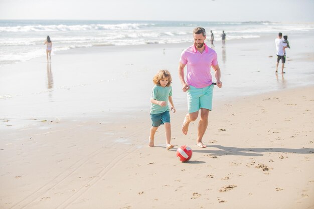 Enfant souriant et papa courant sur la plage en vacances d'été avec ballon fête des pères