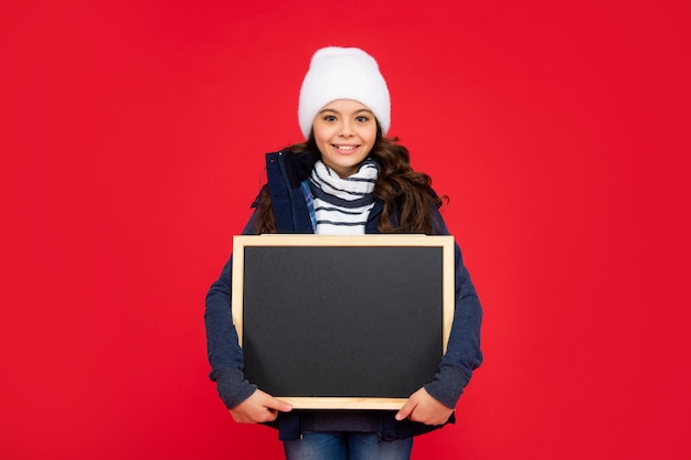 Enfant souriant retour à l'école annonce et publicité vente d'hiver enfant tenir tableau noir