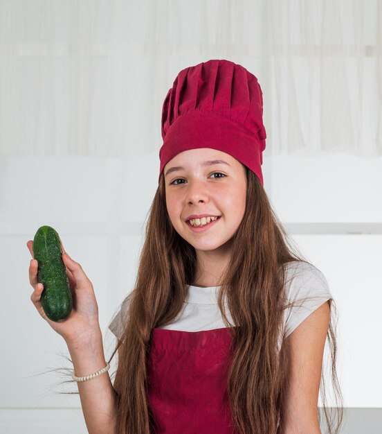 Un enfant souriant tient un cuisinier de concombre