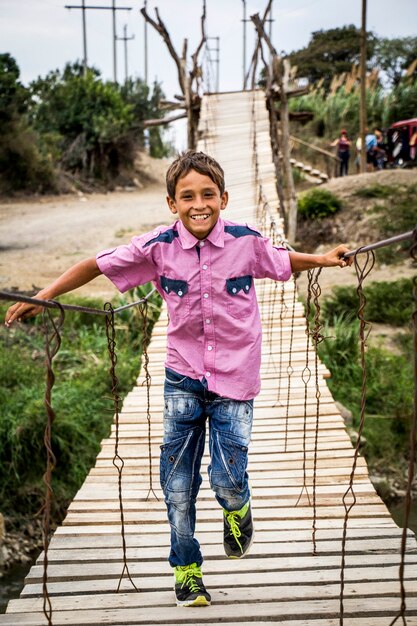 Enfant souriant traversant un pont de bois au Pérou