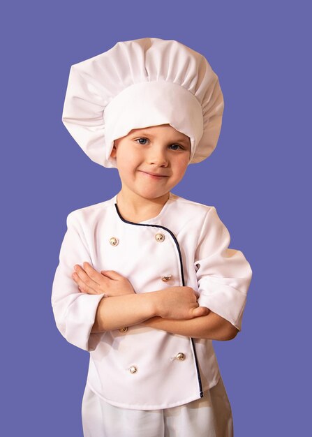 Enfant souriant en uniforme de chef blanc sur fond violet tendance.