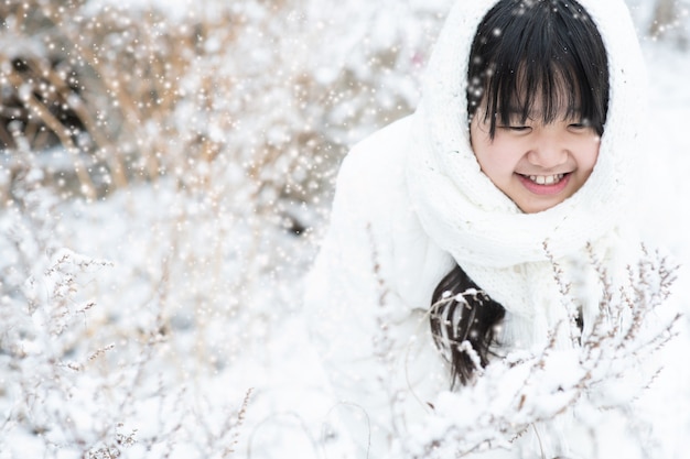 L'enfant sourit brillamment à la neige qui tombe sur l'arbre