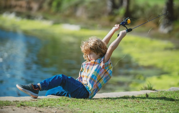 Enfant avec spinner à la rivière Portrait d'un garçon excité à la pêche Garçon à la jetée avec canne Concept de pêche