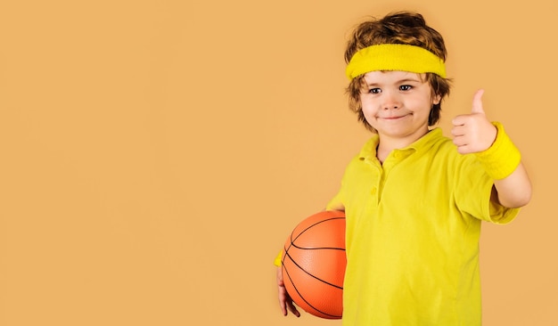 Enfant sportif avec ballon de basket montrant le pouce vers le haut petit joueur de basket-ball en vêtements de sport