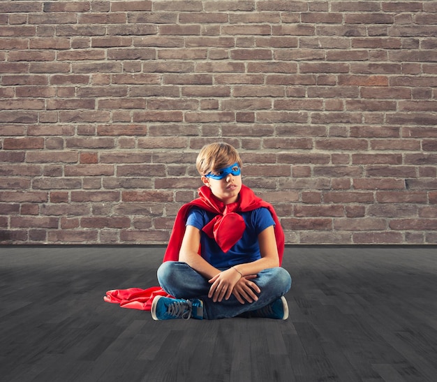 Enfant de super-héros assis sur un mur qui rêve