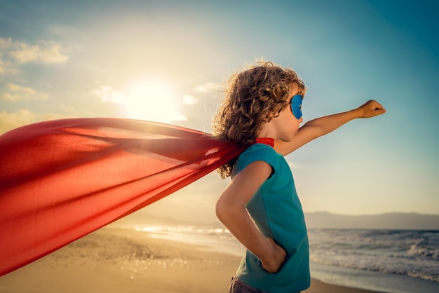 Enfant super-héros sur la plage Enfant super-héros s'amusant en plein air Concept de vacances d'été