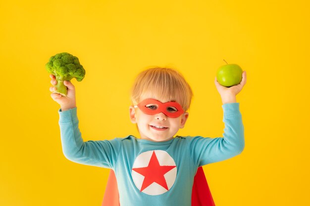 Enfant de super-héros tenant le brocoli et la pomme