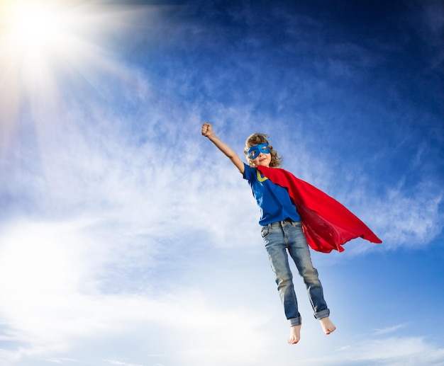 Enfant de super-héros volant sur fond de ciel bleu dramatique