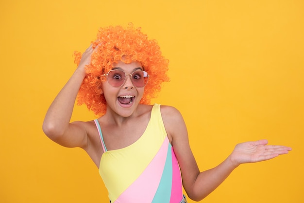 Enfant surpris en lunettes de soleil et perruque de maillot de bain présentant la surprise de l'espace de copie du produit