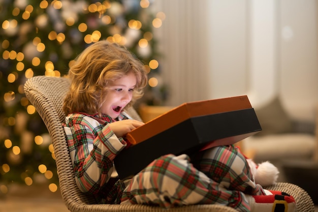 Enfant surprise ouvrant une boîte-cadeau de cadeau de noël enfant se préparant pour les vacances de noël et du nouvel an