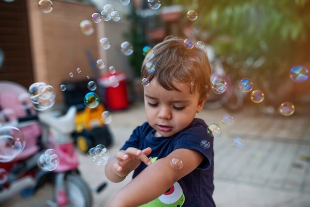 Enfant avec t-shirt bleu jouant avec des bulles de savon