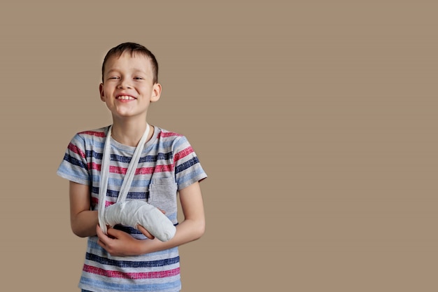 Un enfant en t-shirt rayé avec un bandage enroulé autour de son bras. Blessure au bras.