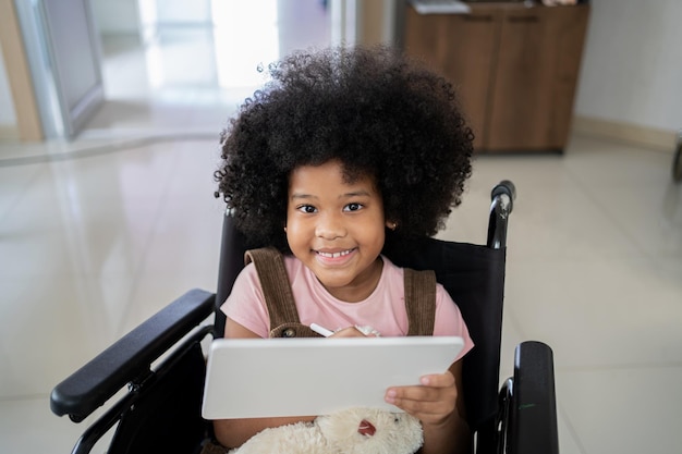 Enfant avec tablette et assis sur un fauteuil roulant. Santé et bien-être d'un patient à l'hôpital.