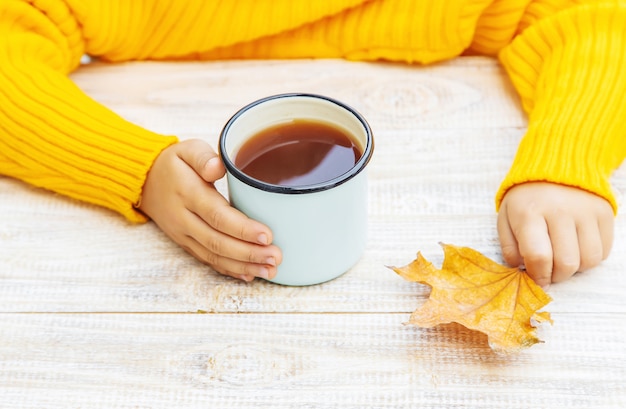 Enfant avec une tasse de thé dans ses mains.